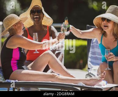 Des femmes heureuses et des amies de haut niveau buvant du champagne sur le patio ensoleillé d'été Banque D'Images