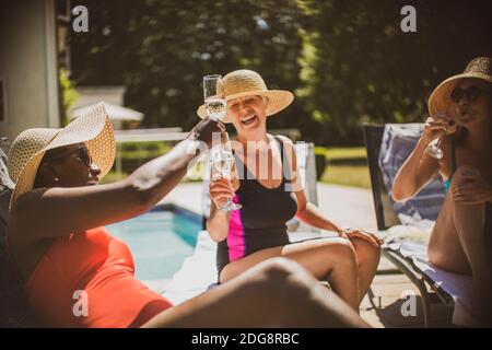 Des femmes heureuses et séniors se sont fait une joie de déguster du champagne au bord de la piscine Banque D'Images