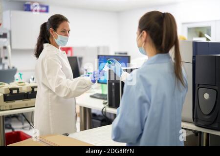 Femmes scientifiques dans des masques faciaux tenant des échantillons en laboratoire Banque D'Images