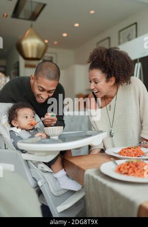 Bon couple qui nourrit bébé fille en chaise haute Banque D'Images