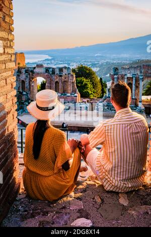 Taormina Sicile, couple regardant le coucher du soleil sur les ruines de l'ancien théâtre grec de Taormina, Sicile. Couple mi-âge sur les vacances Sicilia Banque D'Images