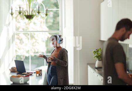 Femme avec casque vidéo conférence à l'ordinateur portable dans la cuisine Banque D'Images