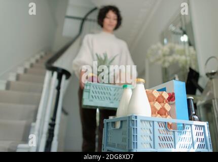 Femme recevant des caisses de livraison d'épicerie dans le foyer Banque D'Images