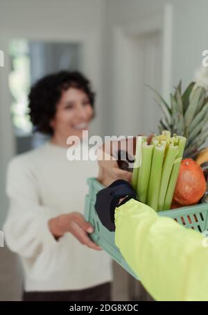 Femme recevant une livraison d'épicerie par un service de messagerie Banque D'Images