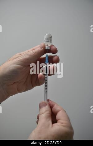 Un membre du personnel prépare un flacon du vaccin Covid-19 Pfizer/BioNTech avant son administration dans un centre de vaccination de Cardiff, le premier jour du plus grand programme d'immunisation de l'histoire du Royaume-Uni. Les travailleurs à domicile, le personnel du NHS et les personnes âgées de 80 ans et plus ont commencé à recevoir le jab ce matin. Banque D'Images