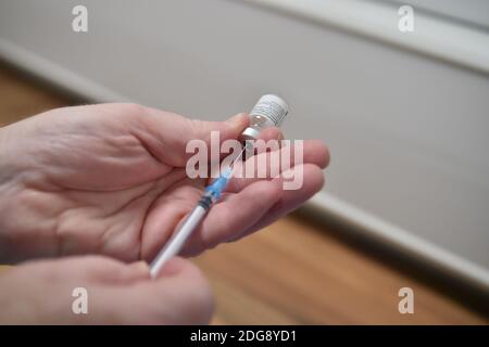 Un membre du personnel prépare un flacon du vaccin Covid-19 Pfizer/BioNTech avant son administration dans un centre de vaccination de Cardiff, le premier jour du plus grand programme d'immunisation de l'histoire du Royaume-Uni. Les travailleurs à domicile, le personnel du NHS et les personnes âgées de 80 ans et plus ont commencé à recevoir le jab ce matin. Banque D'Images