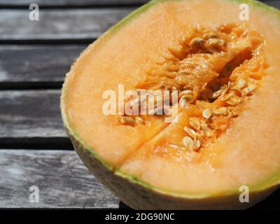 Melon jaune coupé en deux gros plan sur une table rustique en bois noir Banque D'Images