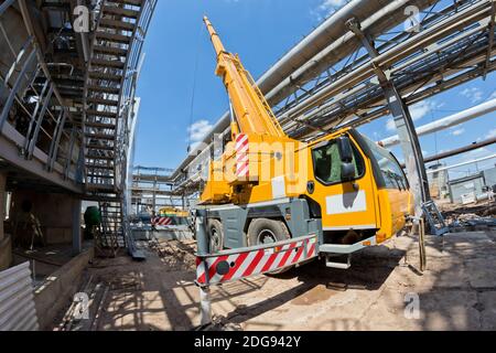 Grue de camion avec jambes étalées et flèche allongée est sur le chantier Banque D'Images
