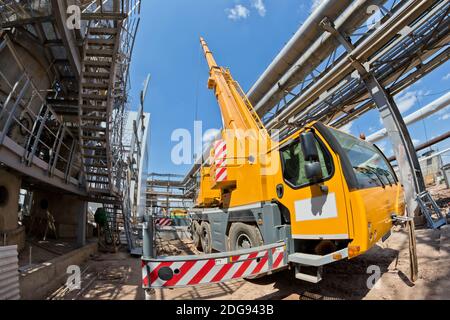 Grue de camion avec jambes étalées et flèche allongée est sur le chantier Banque D'Images