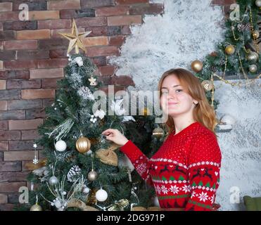 Fille dans la chambre décorer l'arbre de Noël avec des jouets Banque D'Images