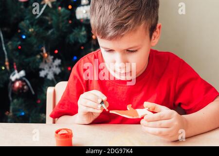 Mignon 7 ans enfant garçon peint en bois dinosaure jouet Pour arbre de Noël Banque D'Images