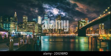 New York City Pont de Brooklyn et Manhattan skyline illuminée la nuit avec la pleine lune au-dessus. Banque D'Images