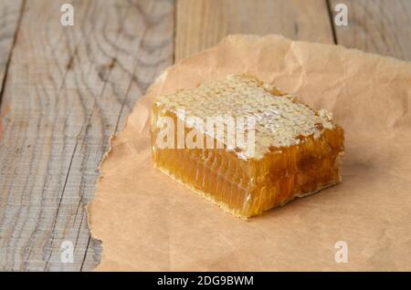 Miel en nid d'abeille sur papier d'emballage sur une table en bois. Mise au point sélective. Banque D'Images