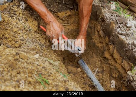 Homme appliquant du solvant primaire et ciment sur les tuyaux en PVC comme Partie de l'installation d'un système d'arrosage automatique souterrain Banque D'Images