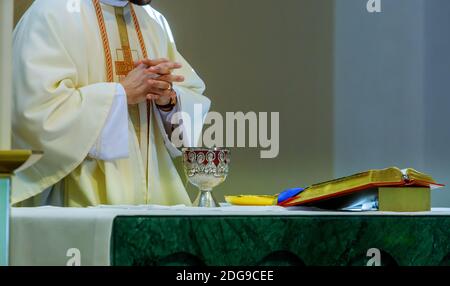 Sainte communion à table dans une tasse de verre d'église avec vin rouge, pain, prière pour le vin Banque D'Images