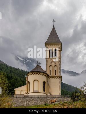 Un cheval brun tombe près de l'église paroissiale de Solda, dans le Tyrol du Sud, en Italie, sous un ciel spectaculaire Banque D'Images