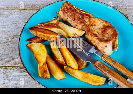 Steak de ribeye marbré moyen-rare grillé coupé en tranches et frit gros plan sur les pommes de terre en quartiers Banque D'Images