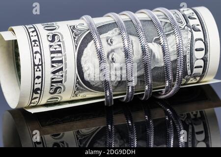 Un billet d'un dollar est enveloppé autour d'une chaîne d'argent avec un filet de serpent Banque D'Images
