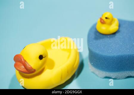 Grand canard en caoutchouc jaune en premier plan avec une éponge bleue derrière avec un petit canard sur le dessus, concept de nettoyage et de bain, vertical Banque D'Images