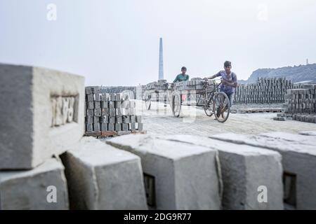 Après le séchage des briques d'argile brute, elles sont empilées à l'intérieur d'un four de briques à cheminée fixe le long de la rivière hazy Turag à Asulia au Bangladesh. La zone est remplie de fours de briques à cheminée fixe, qui viennent de transformer leur production en grande vitesse. Pendant la plus grande partie de l'année, les fours en briques sont inondés car ils sont situés sur les lits de la rivière. Lorsque l'eau recule pendant la saison sèche, les fours reviennent à la vie alors que des centaines d'ouvriers empilent des briques fraîchement pressées en silt dans d'énormes fours à bois et à charbon. En utilisant une technique simple qui remonte des centaines d'années, la cheminée fixe bric Banque D'Images