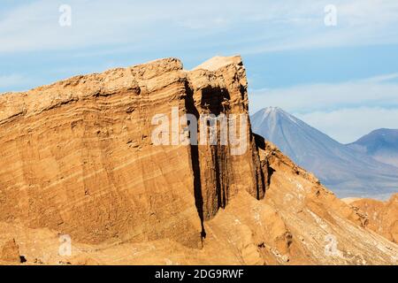 Volcan Licancabur s'élève derrière d'énormes falaises d'orange érodées dans la Valle de la Luna, désert d'Atacama, Chili Banque D'Images