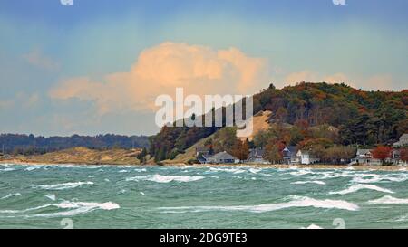 Rive du lac Michigan avec chalets et arbres dans le feuillage d'automne par une journée venteuse avec de grandes vagues Banque D'Images