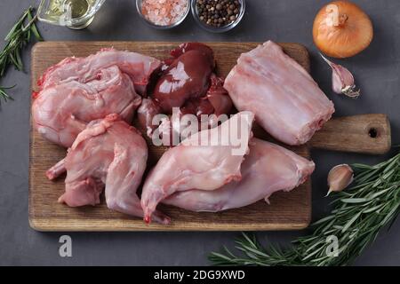 Carcasse de lapin hachée sur une planche de bois et ingrédients frais pour la cuisson. Vue de dessus. Gros plan Banque D'Images