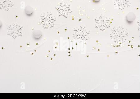 Motif de Noël composé de flocons de neige et d'étoiles dorées sur fond blanc. Concept de vacances d'hiver. Vue de dessus de la mise en plan à plat avec place pour votre texte Banque D'Images