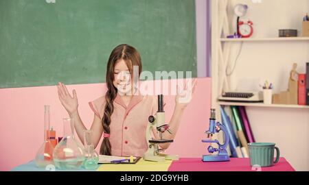 Notre objectif est de trouver le remède. Jeune fille étudier la chimie avec tube à essai. Retour à l'école. Formation en biologie. Leçon de science avec microscope. Laboratoire scolaire. Technologie moderne. Petite fille avec flacon de laboratoire. Banque D'Images