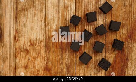 Cubes de charbon de noix de coco pour le narguilé sur fond de bois. Vue de dessus, placer pour le texte Banque D'Images