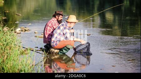 Appât et crochet. Loisirs et loisirs. Bonne prise. Les hommes barbus pêchent. Journée en famille. Chanceux et qualifiés. Pêcher du poisson avec un ami. Les amis pêchent le poisson. Chers pêcheurs. Tourne et s'attaque. Bonne prise. Banque D'Images