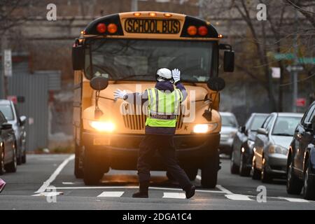 New York, États-Unis. 08 décembre 2020. Un garde-passage d'école tient un autobus tandis que les parents et les enfants se préparent à traverser la rue devant l'école publique 7 Louis F. Simeone dans le quartier Queens de New York, NY, le 8 décembre 2020. Le maire de New York, Bill de Blasio, a annoncé que les écoles primaires et pré-K publiques peuvent reprendre l'apprentissage en personne le 7 décembre, alors que les écoles secondaires et intermédiaires restent fermées; les écoles ont été fermées le 18 novembre, lorsque la ville a dépassé le seuil de taux d'infection de 3 % fixé par le maire de Blasio. (Photo par Anthony Behar/Sipa USA) crédit: SIPA USA/Alay Live News Banque D'Images