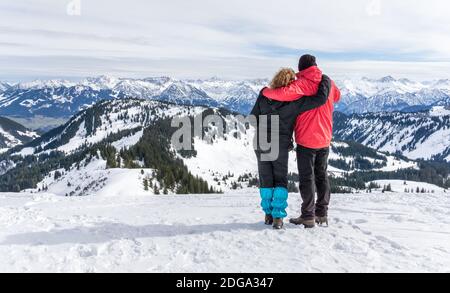 Le couple Senior fait de la randonnée dans les montagnes d'hiver de la neige alpine et bénéficie d'une vue panoramique. Allgau, Bavière, Allemagne. Banque D'Images