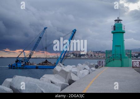 Une barge de grue de construction flotte le long de la côte pendant les travaux de remise en état des terres au large de la côte de Ligurie, en Italie Banque D'Images