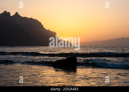 Une belle vue côtière du soleil se coucher derrière la montagne à la plage de Roque de las Bodegas, Tenerife Banque D'Images