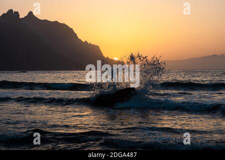 Une belle vue côtière du soleil se coucher derrière la montagne à la plage de Roque de las Bodegas, Tenerife Banque D'Images