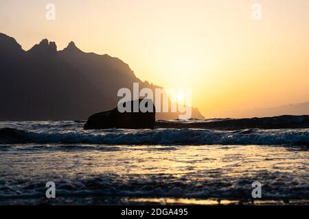 Une belle vue côtière du soleil se coucher derrière la montagne à la plage de Roque de las Bodegas, Tenerife Banque D'Images