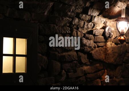 Vue sur un mur d'une ancienne cave en pierre avec lampe et vitre Banque D'Images