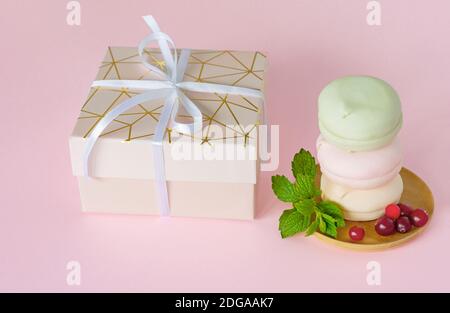 Boîte cadeau avec guimauves multicolores pastel maison. zephyr aux pommes de forme ronde. Délicieux dessert aux fruits sur fond rose. Banque D'Images