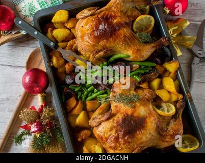 dîner de noël avec volaille rôtie, pommes de terre rôties et haricots verts de princesse servis sur une table avec fourchette de viande et couteau à viande et ornements Banque D'Images