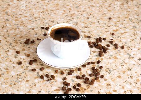 Café fraîchement préparé dans une tasse blanche et grains de café saupoudrées. Banque D'Images
