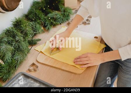 Image rognée d'une femme qui fait des biscuits de Noël sur une table de cuisine. Banque D'Images