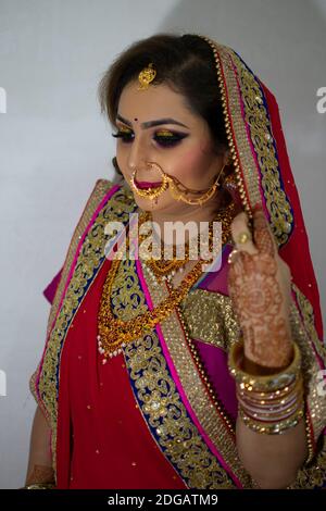 Une belle fille indienne en robe de mariée portant une saree rouge et ornements dorés Banque D'Images