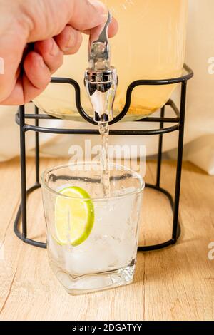 La main de l'homme verse un verre de jus d'agrumes dans un distributeur de boissons. Actionnez la vanne pour fermer et ouvrir le robinet de la bouteille de jus. Banque D'Images