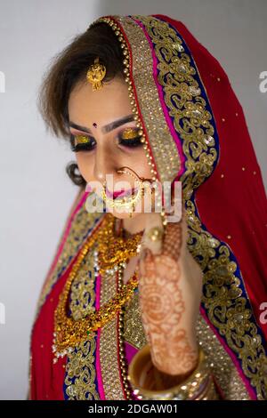 Une belle fille indienne en robe de mariée portant une saree rouge et ornements dorés Banque D'Images