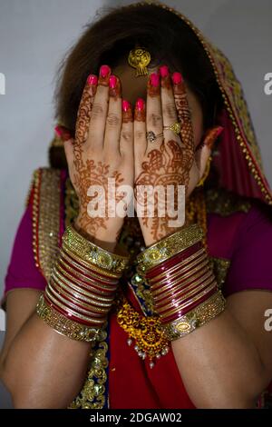 une belle fille indienne en robe de mariée portant une saree rouge et des ornements dorés montrant le tatouage appelé mehindi Banque D'Images
