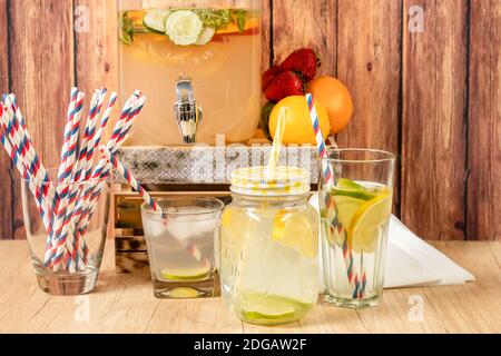 Distributeur de boissons naturelles avec jus d'agrumes faits maison sur une surface en bois, différents types de verres et de cruches avec sorbet et glace avec jus et un Banque D'Images