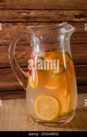 Grand pichet en verre avec eau aromatisée aux agrumes et limonade maison. Verre ou pot avec boisson, couvercle et paille. Fraîcheur, santé et sans alcool Banque D'Images