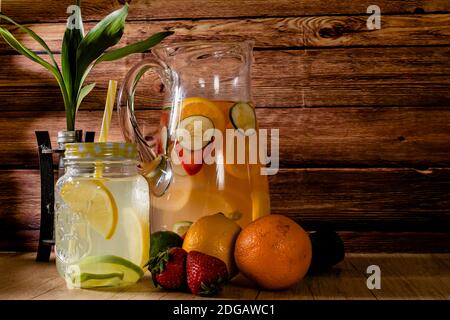 Grand pichet en verre avec eau aromatisée aux agrumes et limonade maison. Verre ou pot avec boisson, couvercle et paille. Fraîcheur, santé et sans alcool Banque D'Images