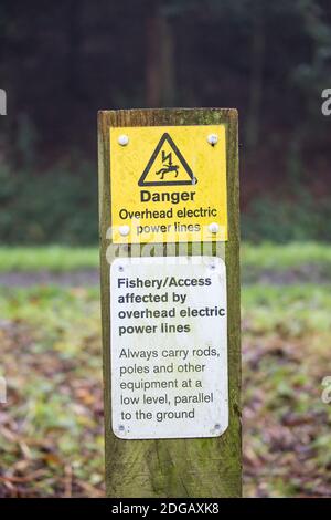 Panneau de danger britannique sur panneau isolé à l'extérieur sur le chemin de remorquage du canal, avertissement pêche, pêche à la ligne publique de lignes électriques aériennes. Banque D'Images